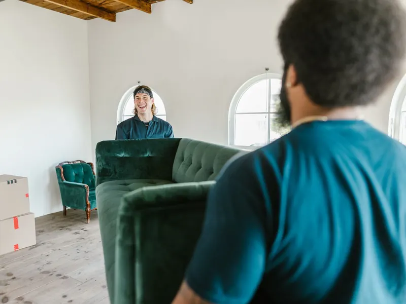 Zwei Helfer tragen ein Sofa aus der Wohnung